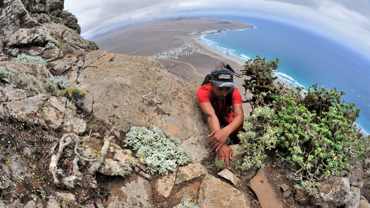 NA RISCO DE FAMARA -  w tle widoczna plaża Famara. Wspinaczka na wielkim klifie wulkanicznej wyspy Lanzarote.