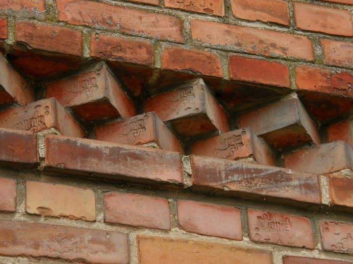 Detal budynku gospodarczego w Marzęcinie. Został wybudowany z kadyńskich cegieł; "logo" wytwórni tworzy swego rodzaju ornament na skromnej elewacji budynku.