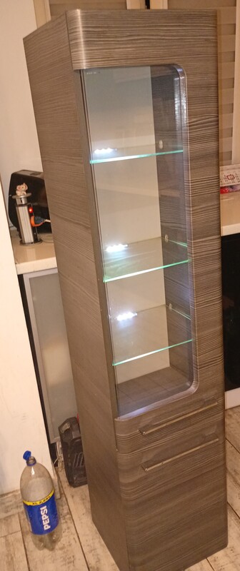 Elbląg Szafka łazienkowa, słupek podświetlana w stanie używanym. Posiada przeszklone drzwi i kilka półek wewnątrz.