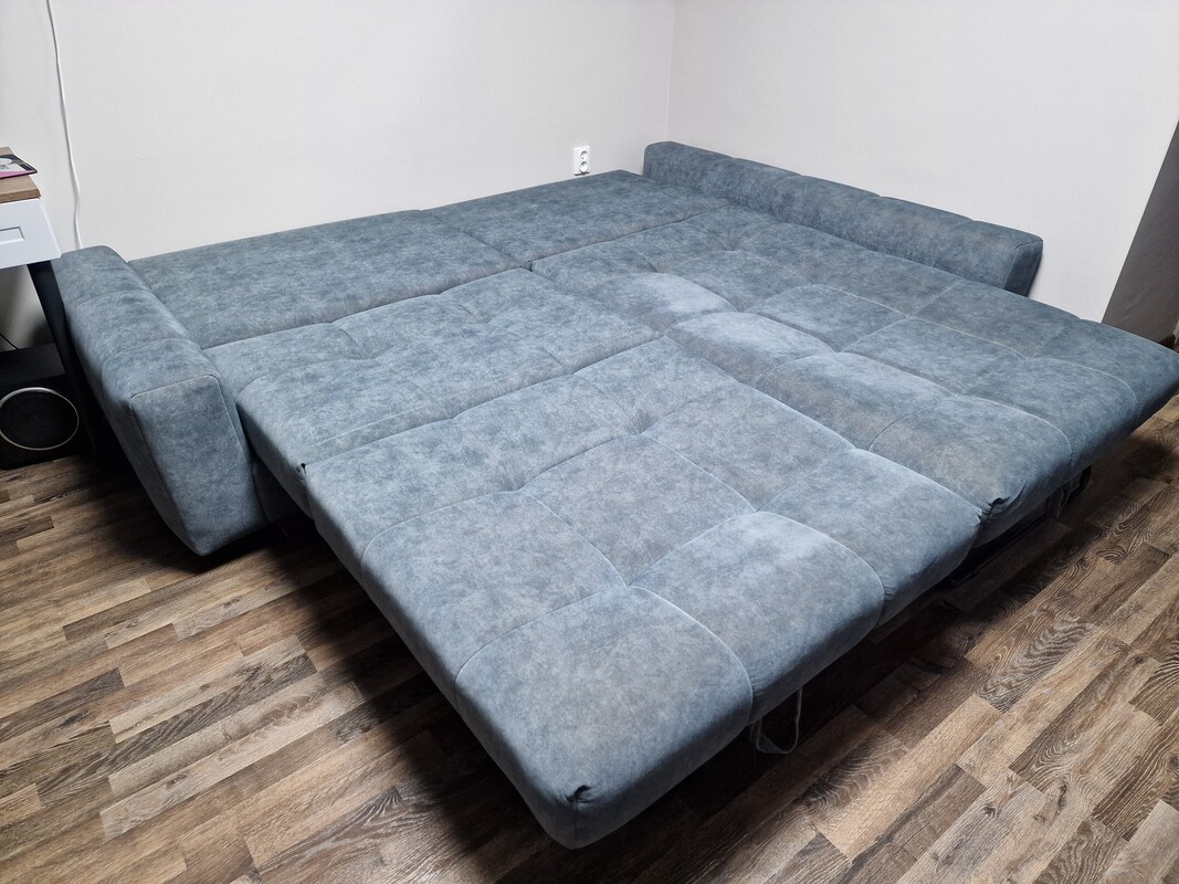 Elbląg Lewy kompaktowy narożnik PICOLLO z funkcją spania z przyjemnej tkaniny w kolorze ciemnej, zgaszonej zieleni.